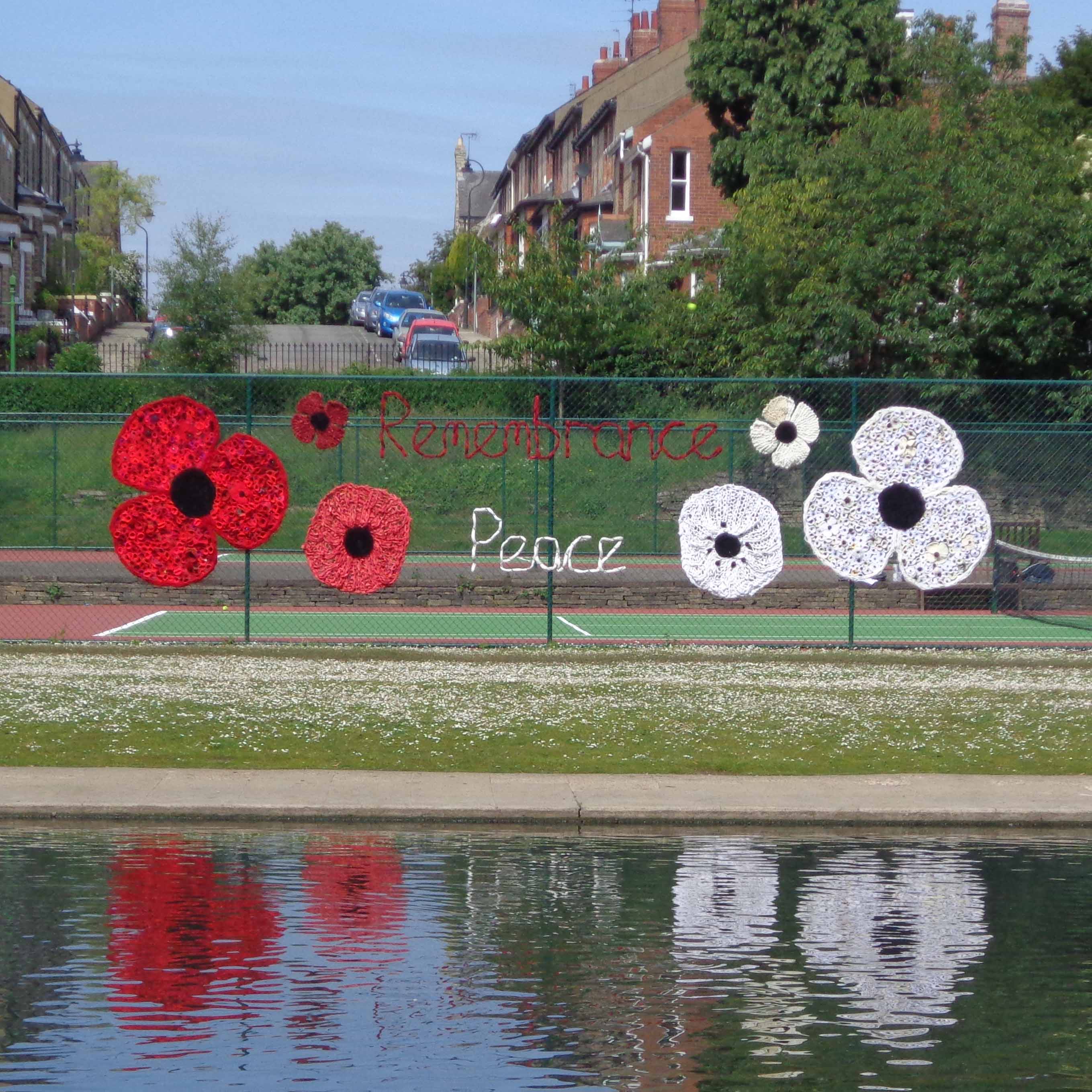 large red and white textile poppies displayed on a chain-link fence