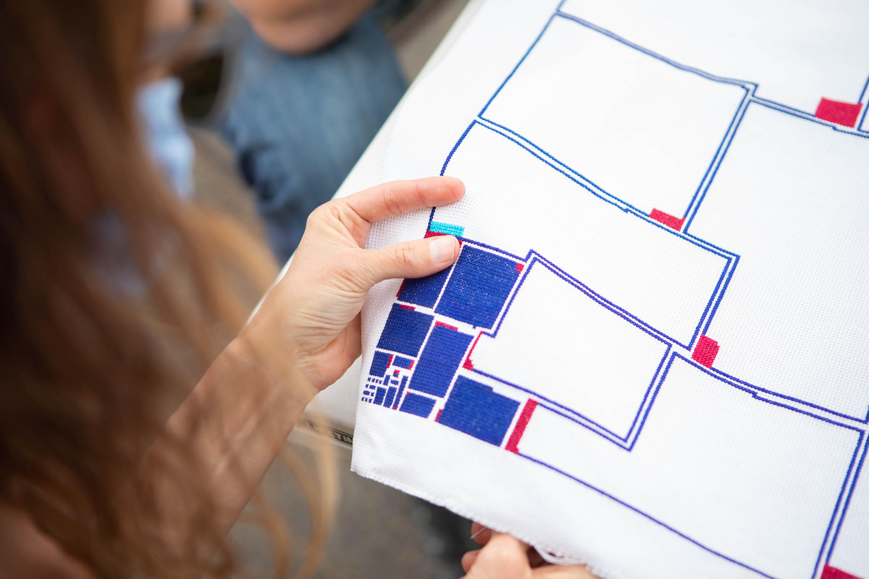 hands holding a geometric cross-stitch embroidery